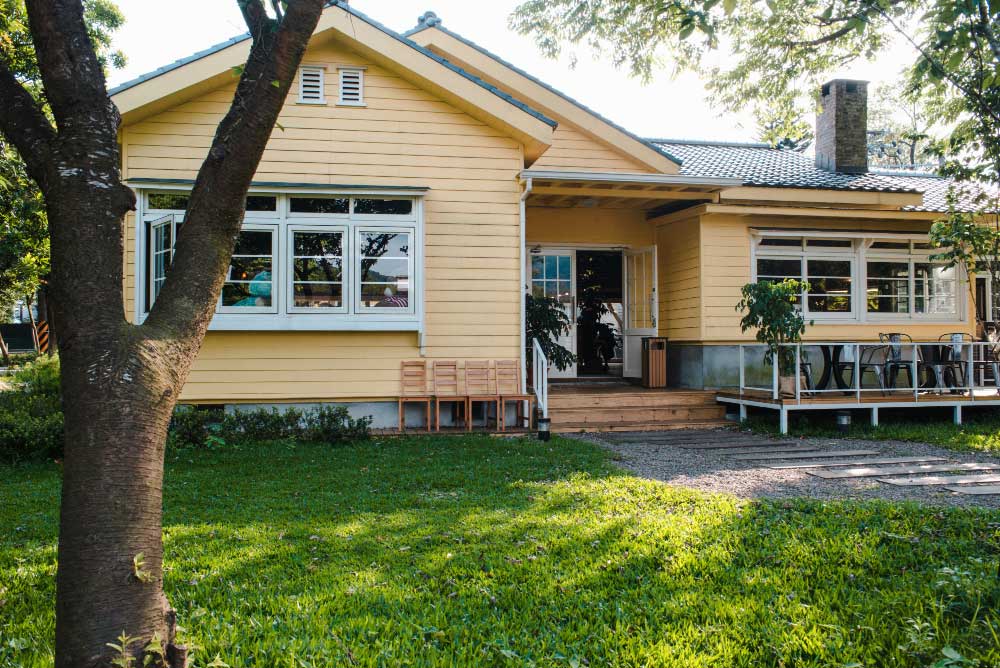 Yellow house with wooden siding and a front porch.